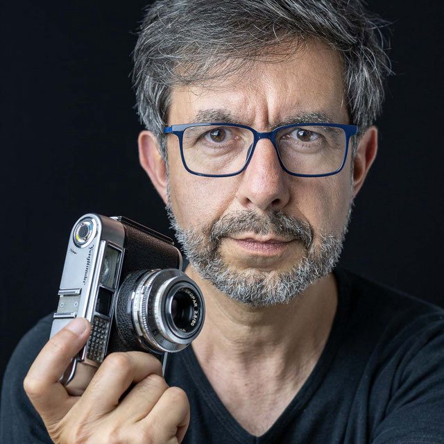 Portrait de Philippe Colin, photographe, tenant un appareil photo vintage Voigtländer